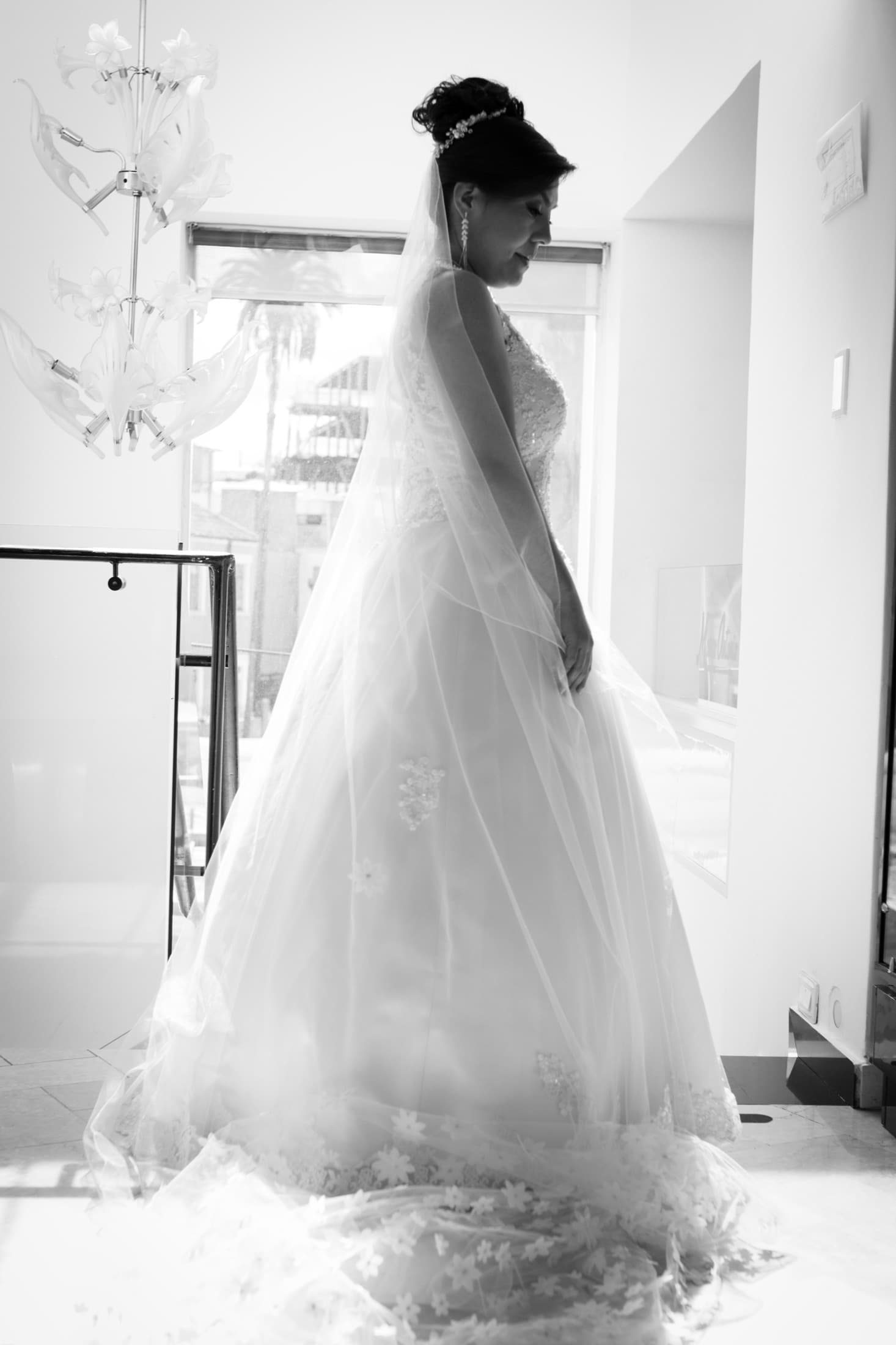 Novia de perfil a contraluz junto a una ventana, en blanco y negro