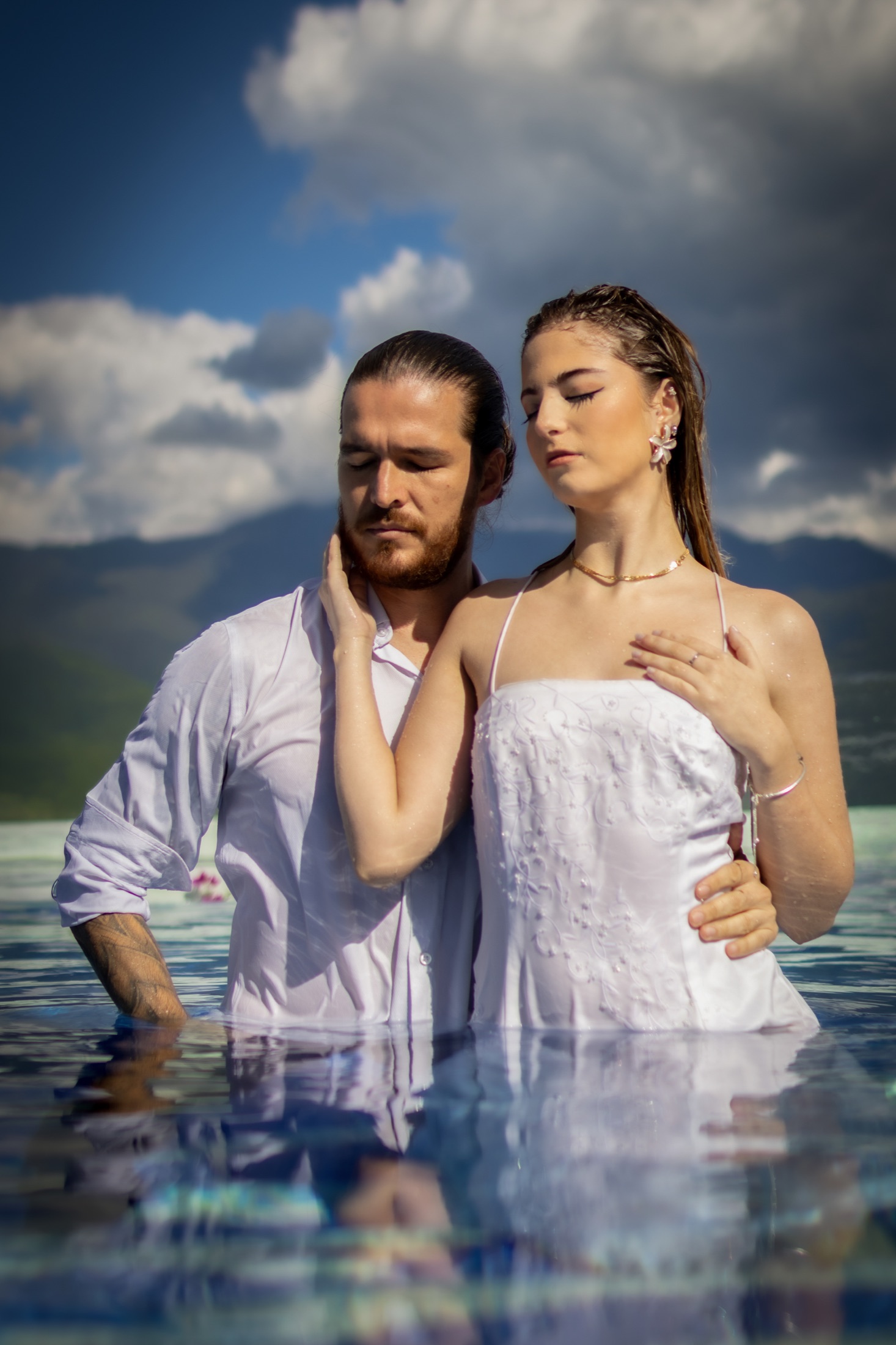 Pareja de novios abrazados en una piscina infinita frente a las montañas