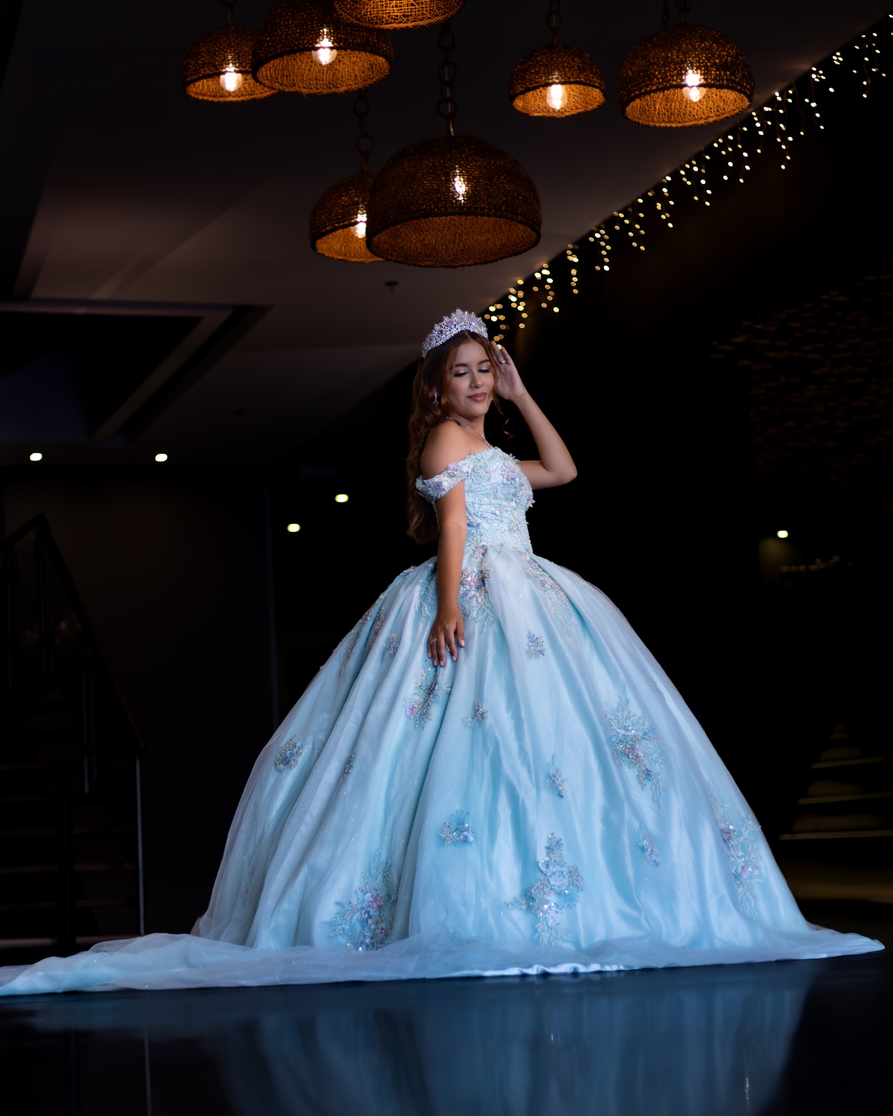 Quinceañera ajustándose la tiara con vestido azul claro