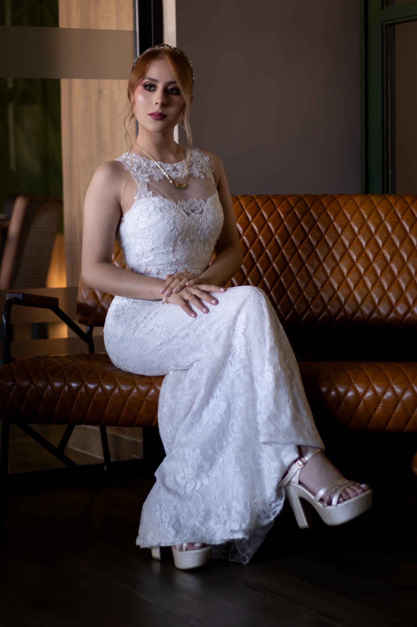 Novia sentada en un sofá de cuero ajustando sus zapatos