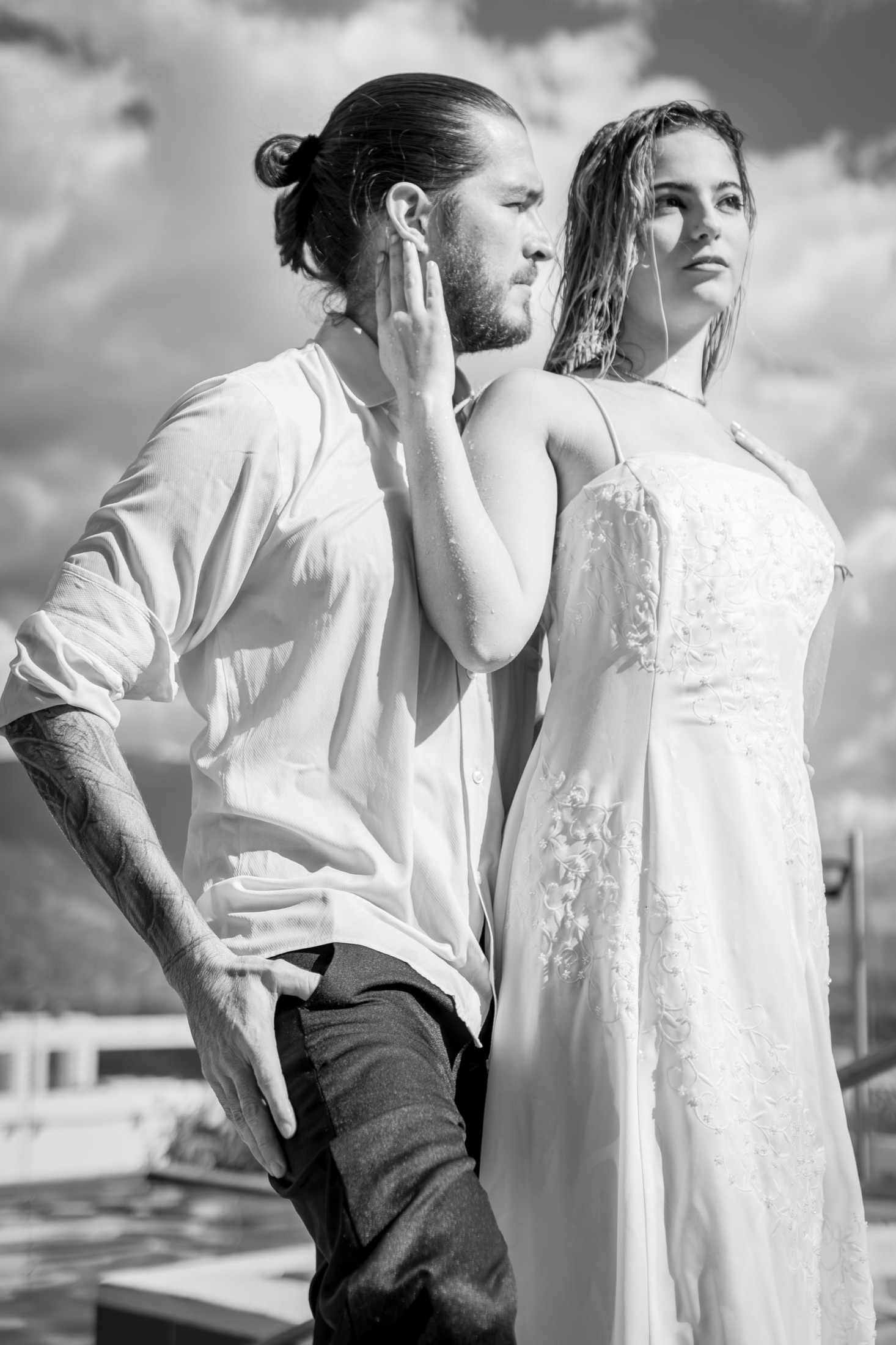 Pareja de novios espalda con espalda en blanco y negro junto a una piscina