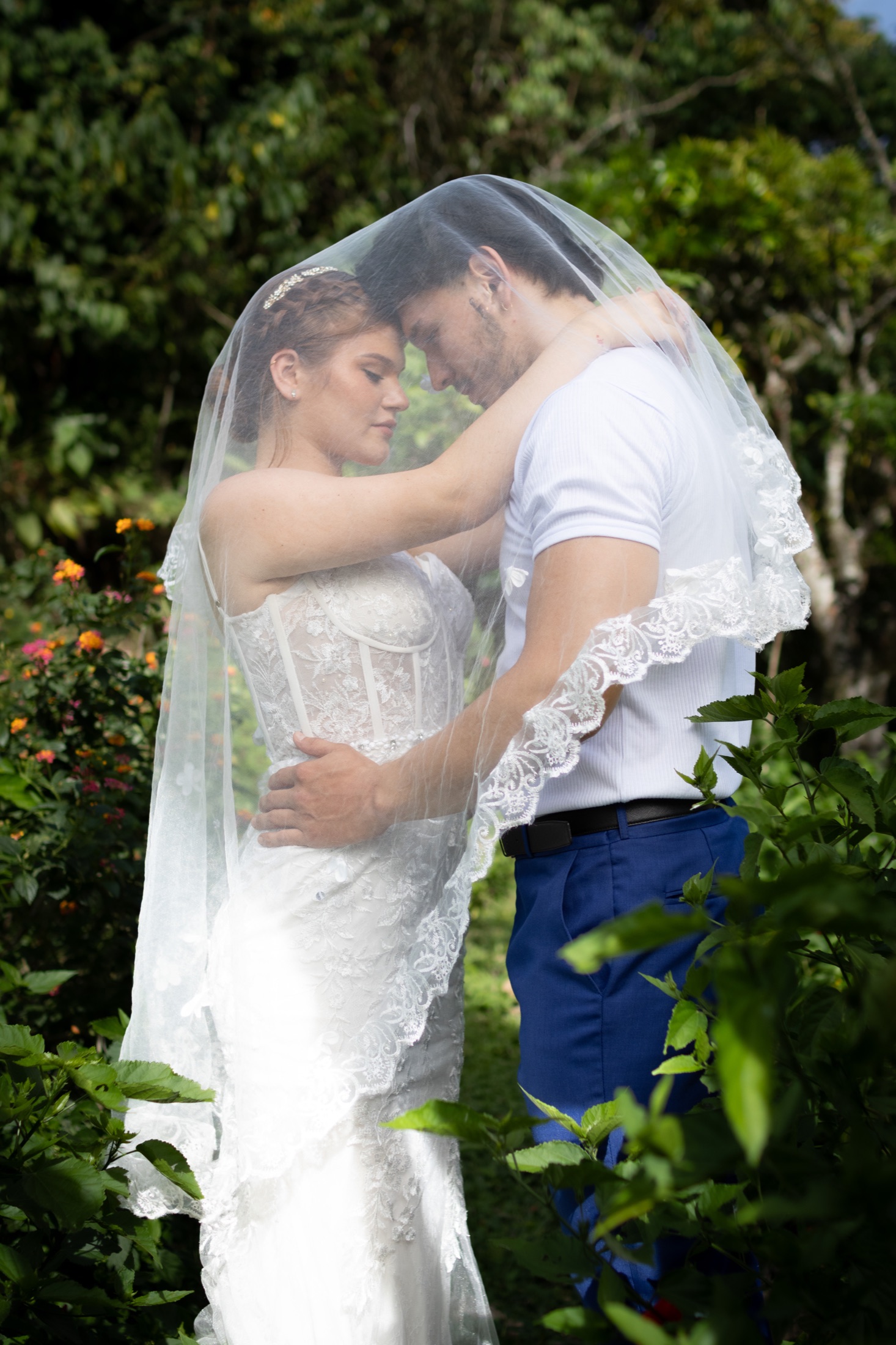 Pareja de novios abrazados bajo el velo, frente con frente
