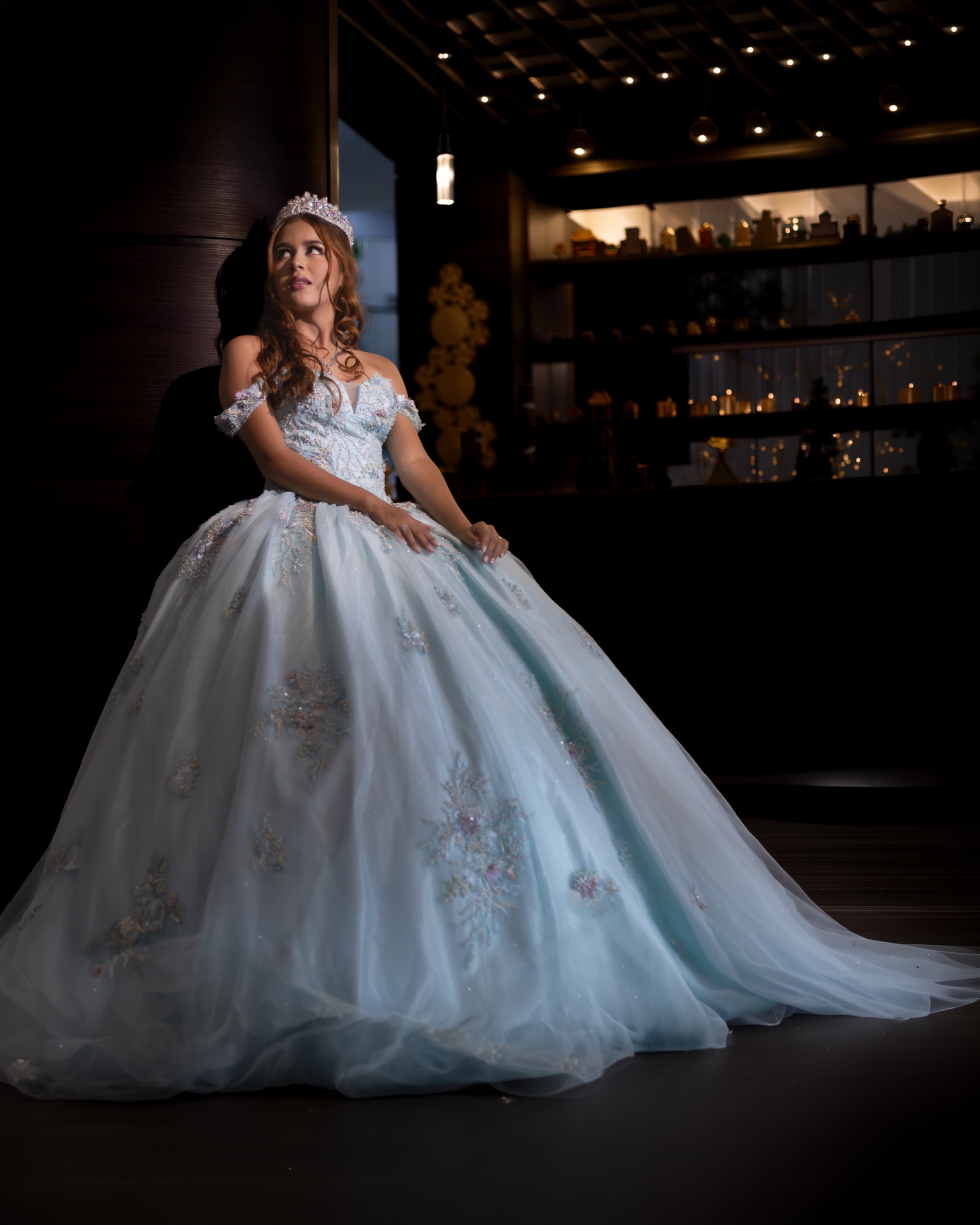 Quinceañera apoyada contra una pared, mirando hacia arriba