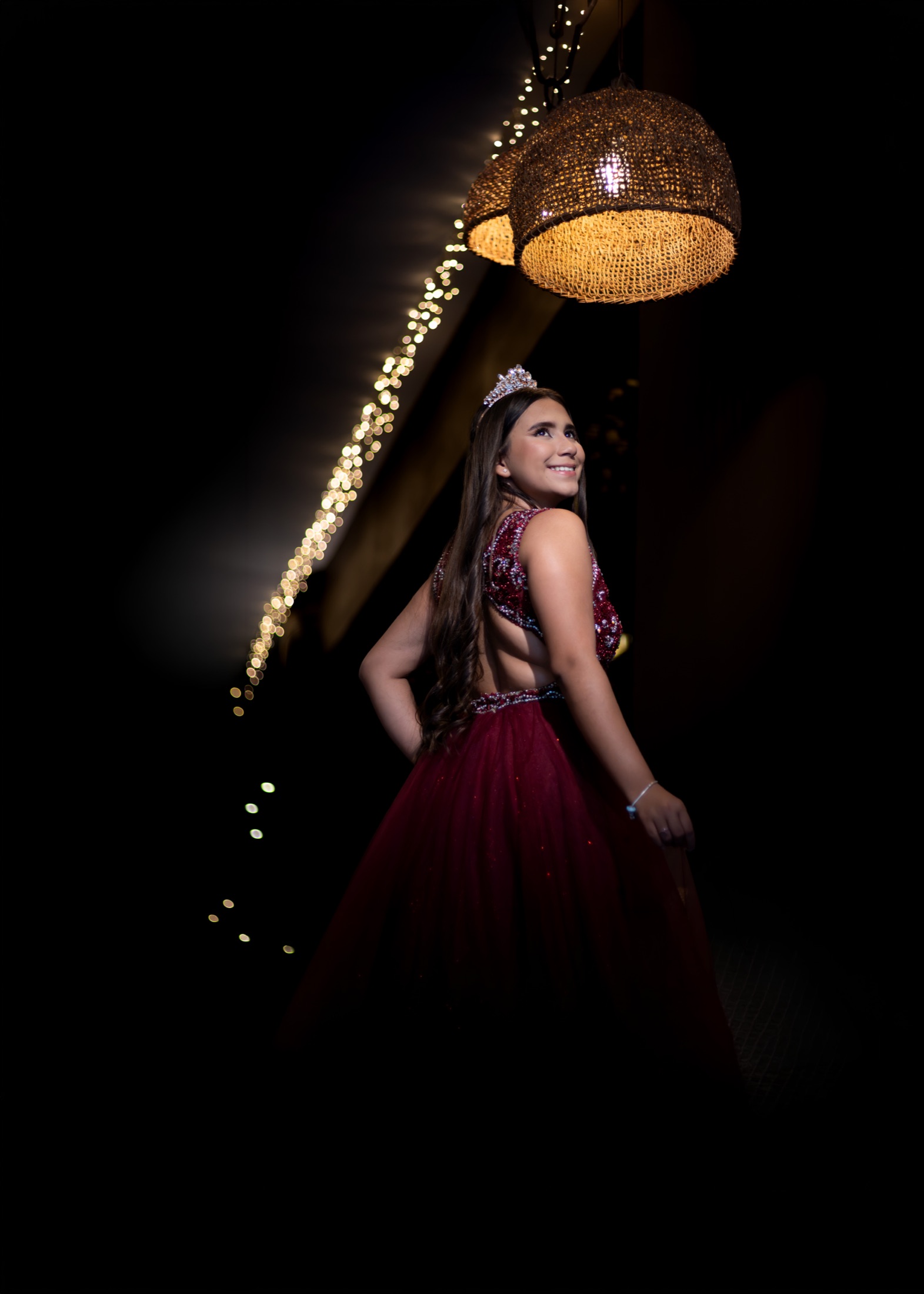 Quinceañera con vestido rojo de espalda descubierta bajo las luces